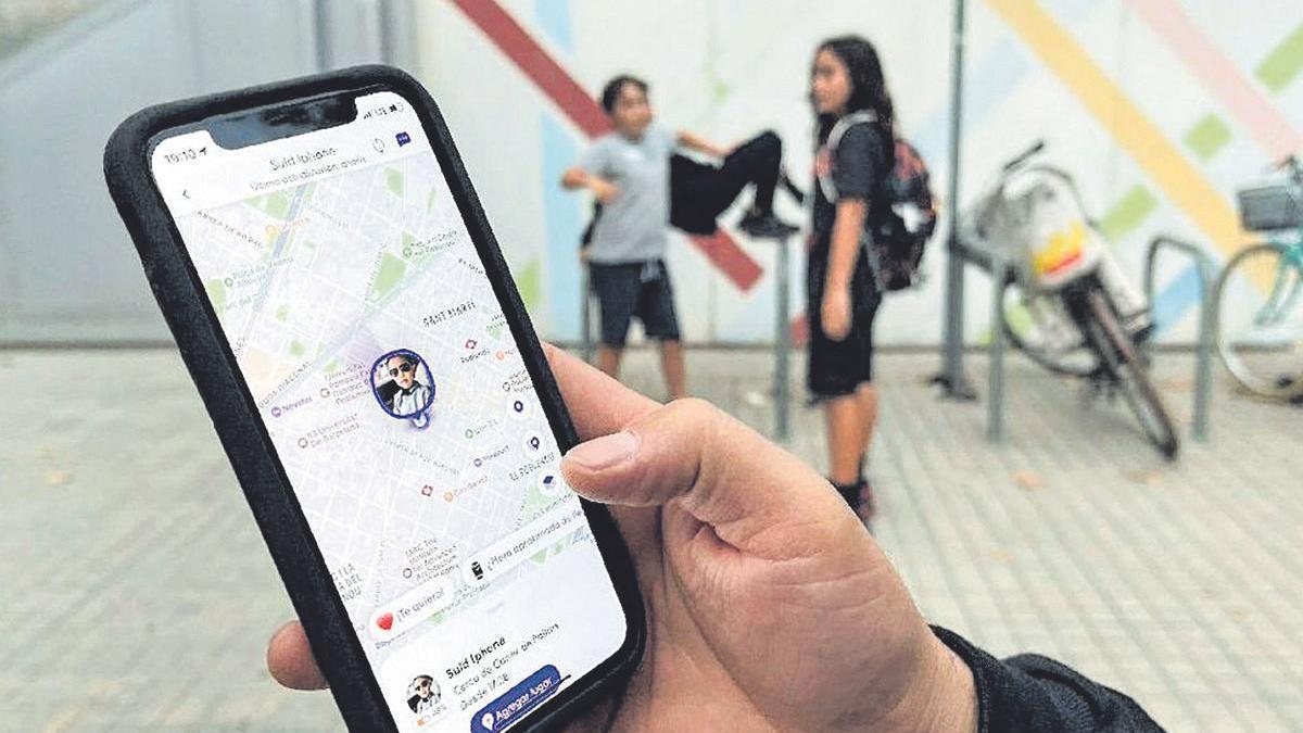 Un pare observa el seu telèfon mòbil, on té una aplicació per localitzar els seus fills