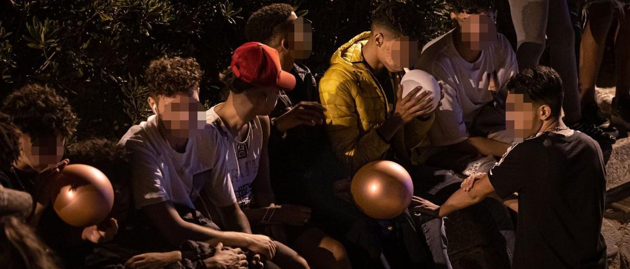 Varios jóvenes inhalan óxido nitroso con globos en el macrobotellón de la playa de Bogatell.