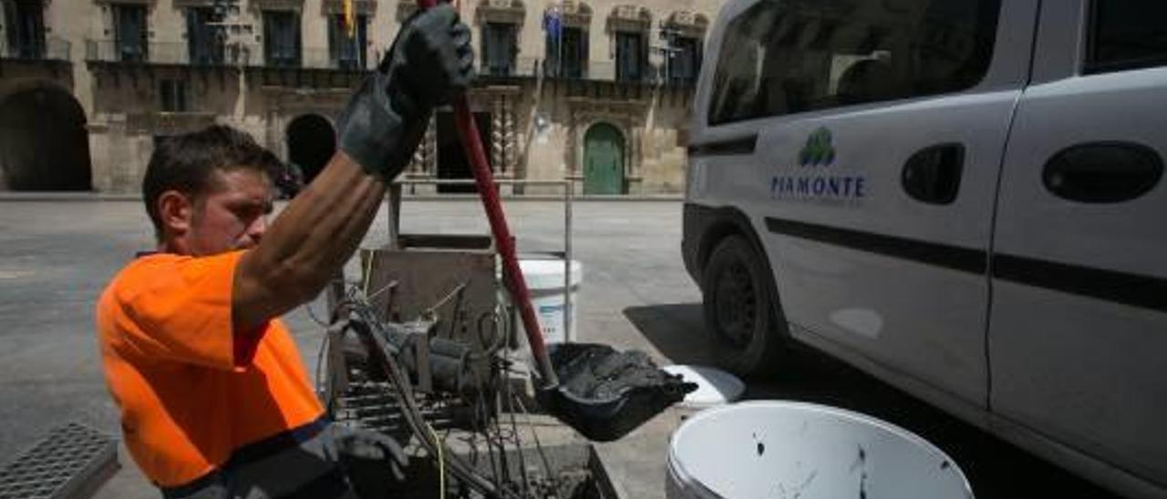 Un operario retira ceniza de los chorros de la plaza del Ayuntamiento