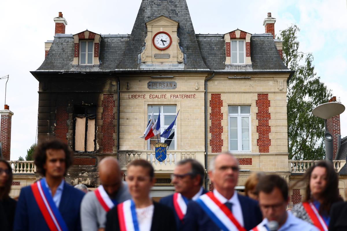 Ciudadanos se congregan ante la alcaldía semidestruida por las llamas de Persan, cerca de París.