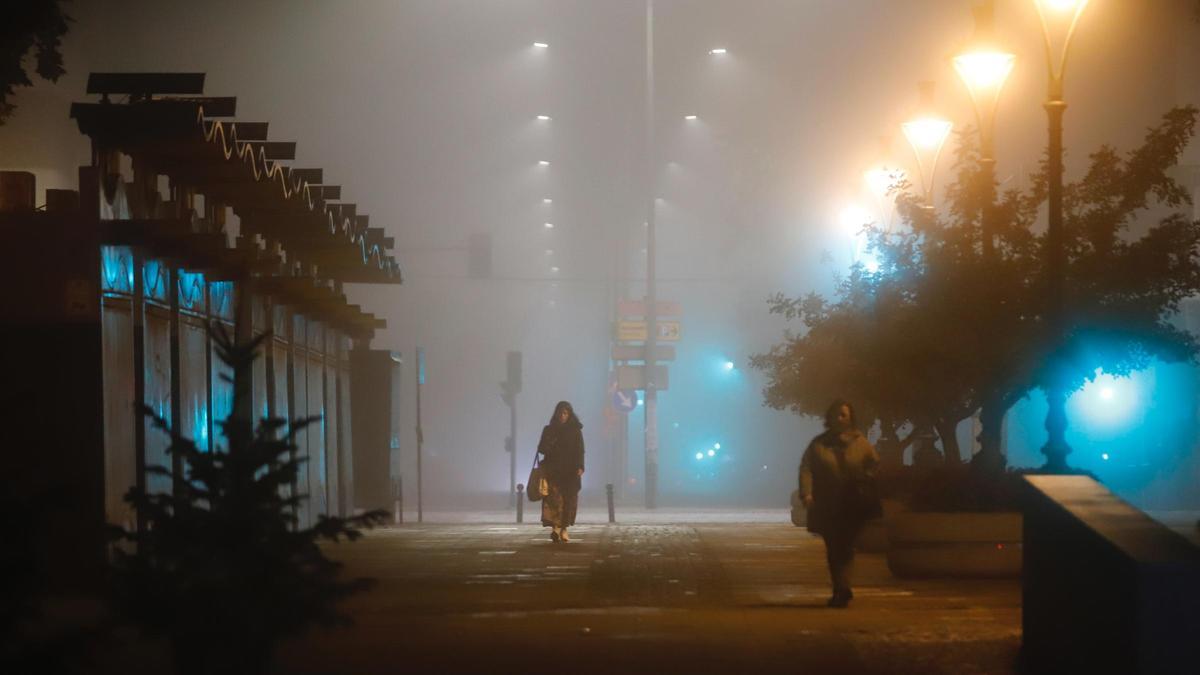 Varios transeúntes bajo la niebla en Córdoba.