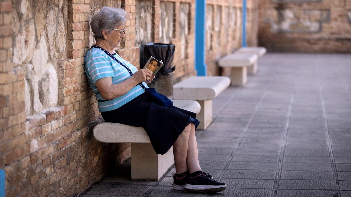 Una mujer lee, sentada en un banco.