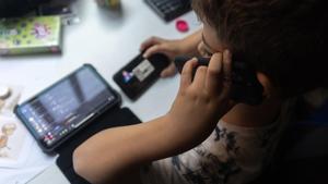 Un niño usa el teléfono móvil y una tablet.