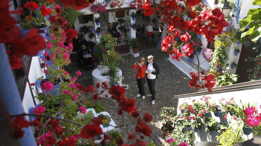 Dos turistas, en un patio decorado con flores en Córdoba.