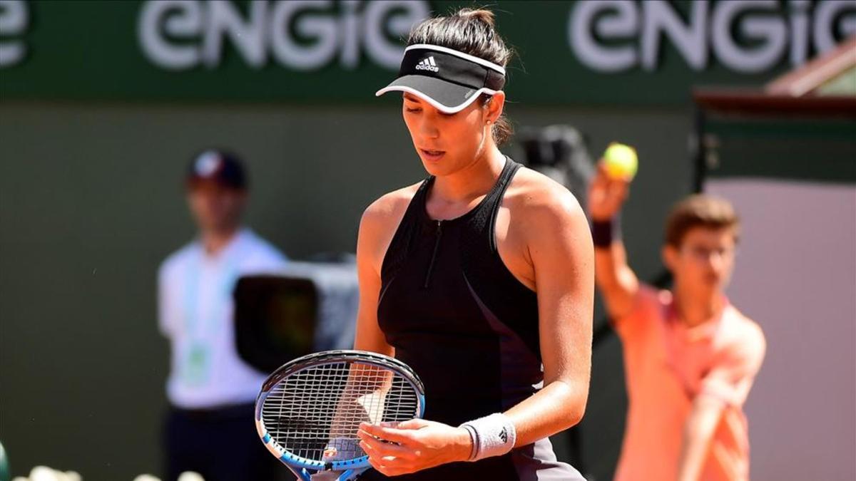 Muguruza obersva y ajusta el cordaje de su raqueta