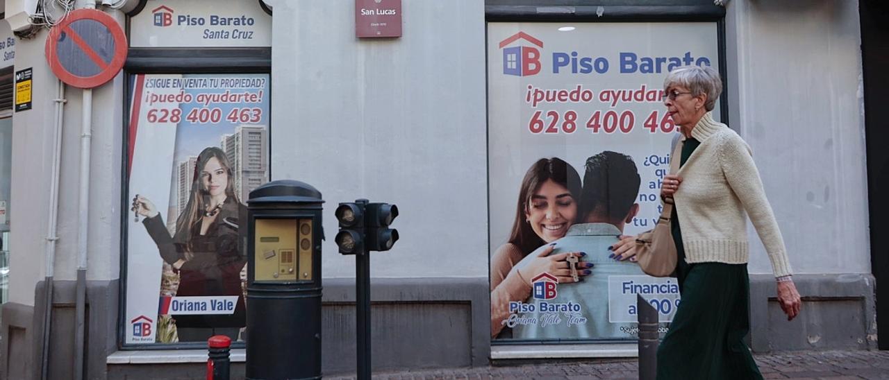 Una mujer pasa ante los anuncios de una firma inmobiliaria en una calle de Santa Cruz de Tenerife.