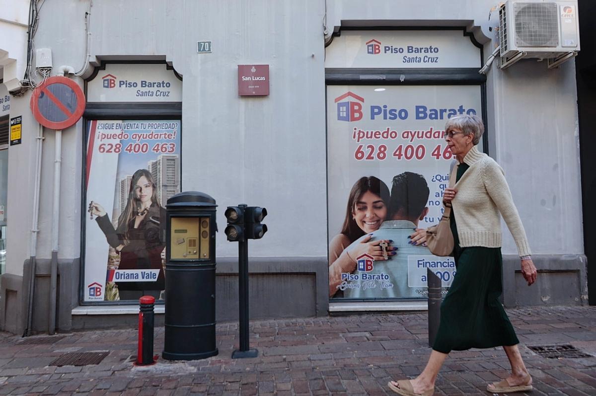 Una mujer pasa ante los anuncios de una firma inmobiliaria en una calle de Santa Cruz de Tenerife.