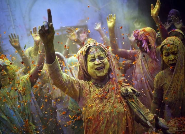 Viudas embadurnadas con colores bailan como parte del Festival de Holi