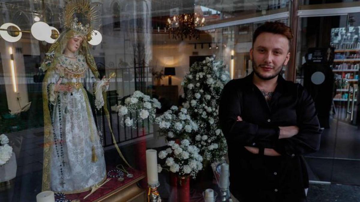 l peluquero Agustín Hernández junto al escaparate que ha tematizado en honor a la Virgen de La Soledad.