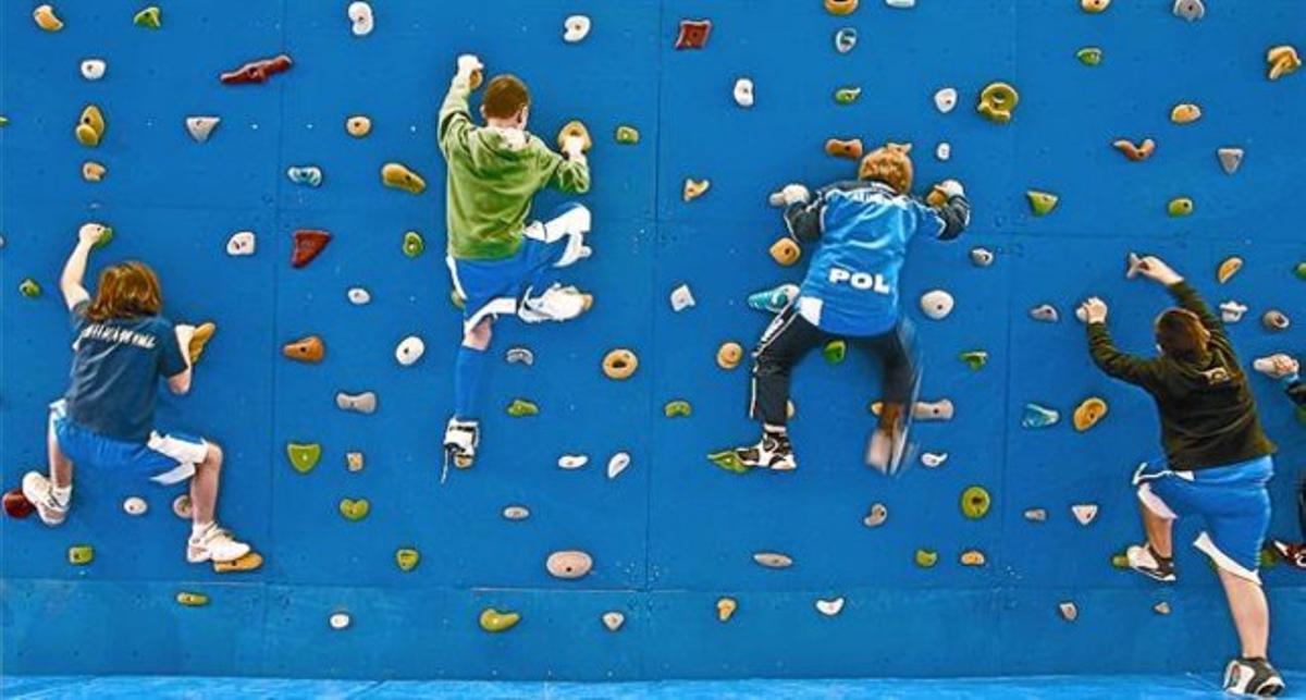 Ejercicio 8 Cuatro chavales practican escalada deportiva en una pared, ayer, en el Festival de la Infancia.