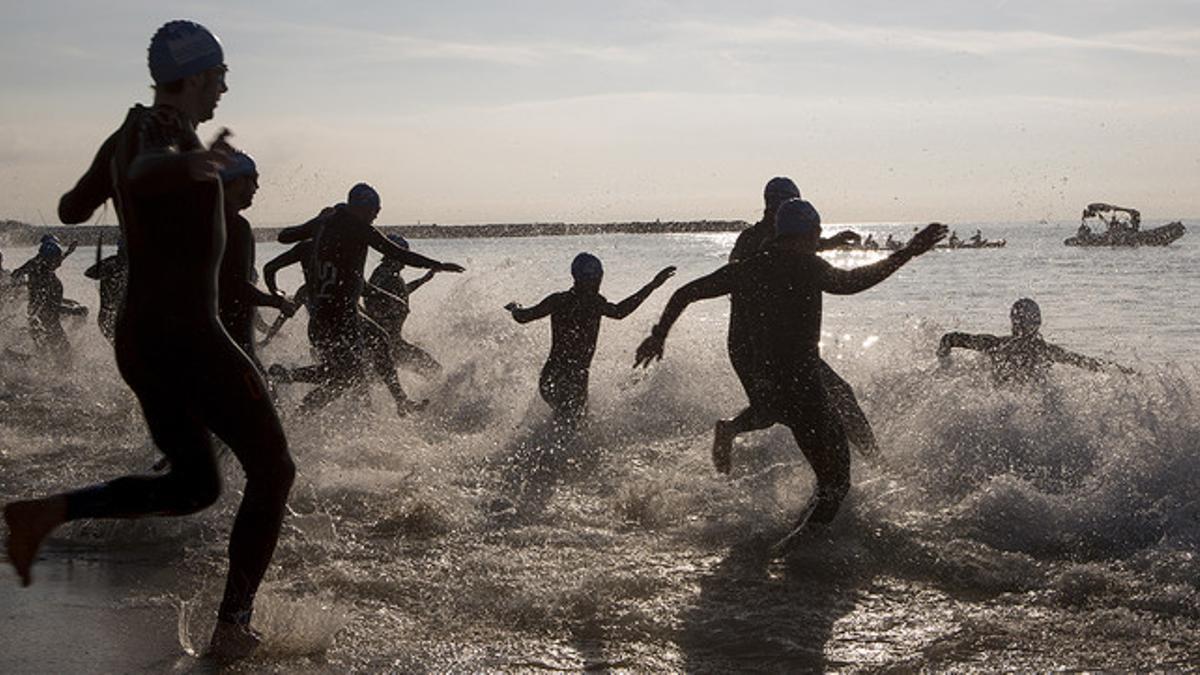 Los participantes en el Triatlón de Barcelona se lanzan al mar, con trajes de neopreno