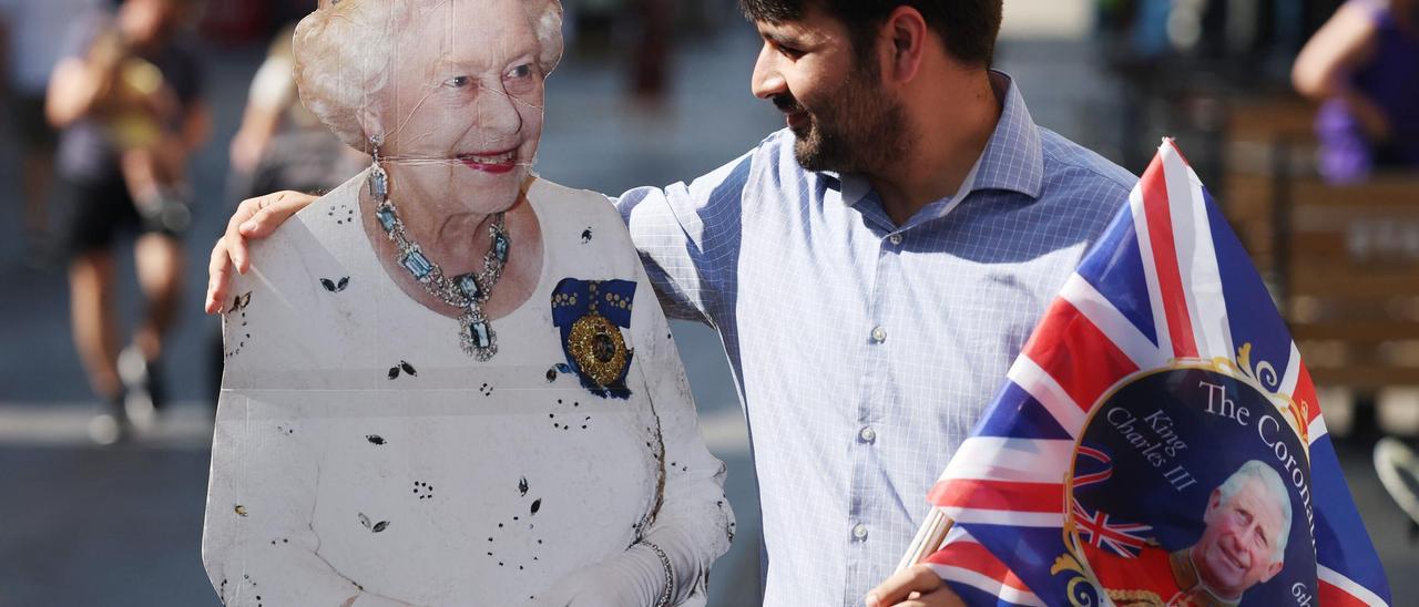 Un hombre posa con una fotografía a tamaño real de Isabel II y unos banderines de la coronación de Carlos III, este jueves en Windsor.