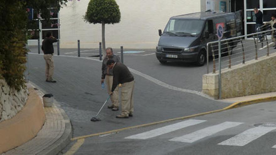 Dos trabajadores municipales limpian la sangre del sitio donde ha tenido lugar el accidente, frente al centro de salud