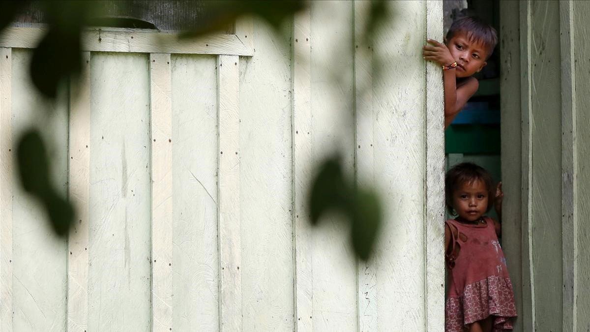 Dos niños de la etnia yanomami se asoman tras un muro.