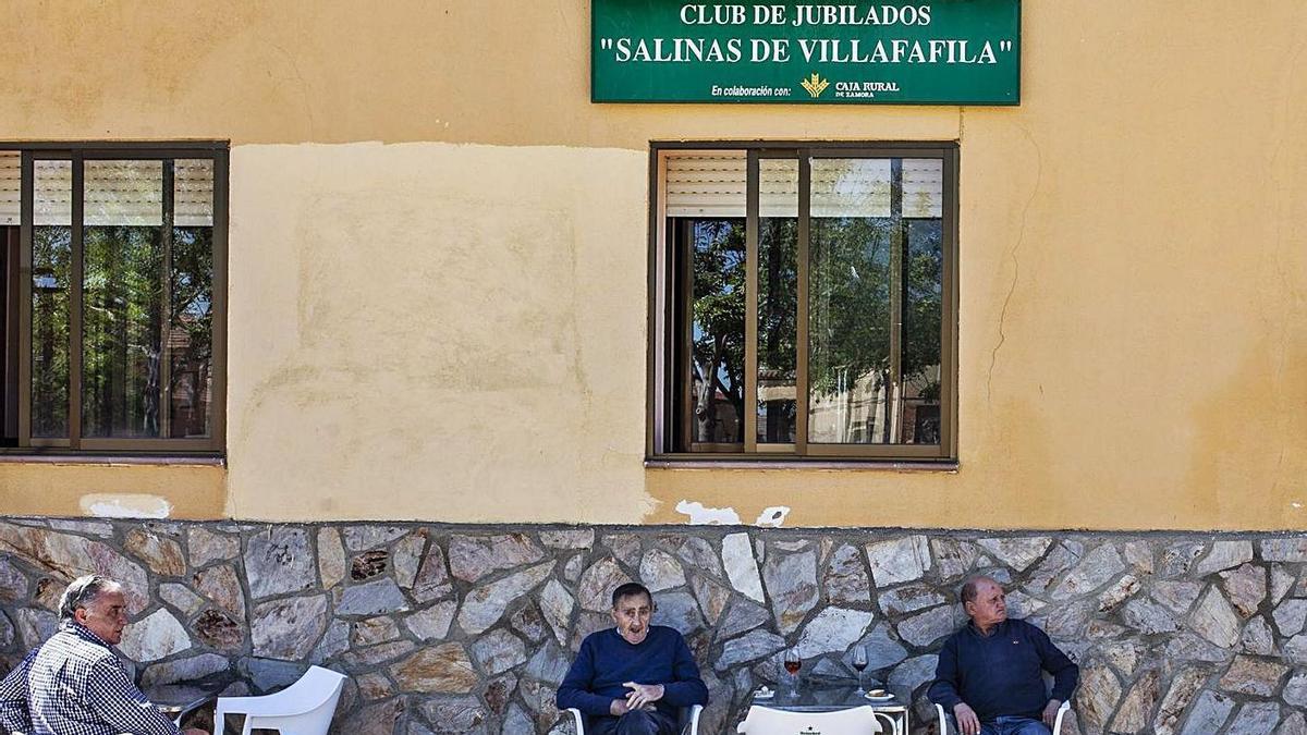 Varias personas sentadas frente a un club de jubilados de la provincia.