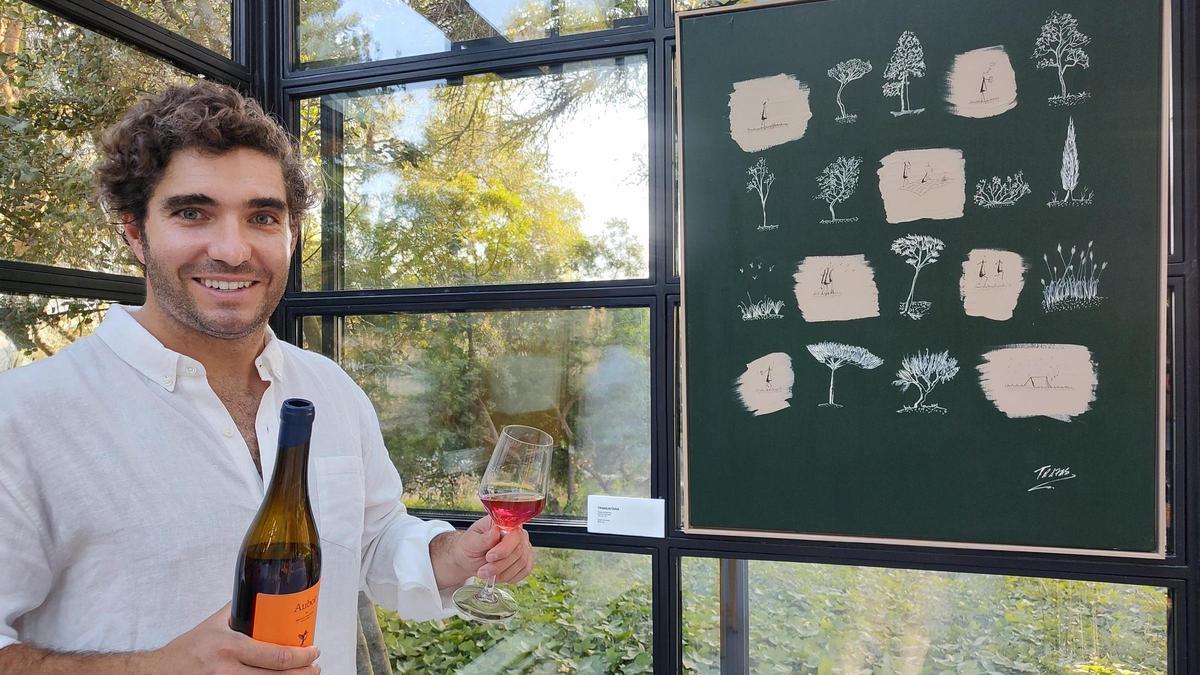 El artista Trazas, junto a una de sus obras y el vino Aubor, de la viña de Montuïri