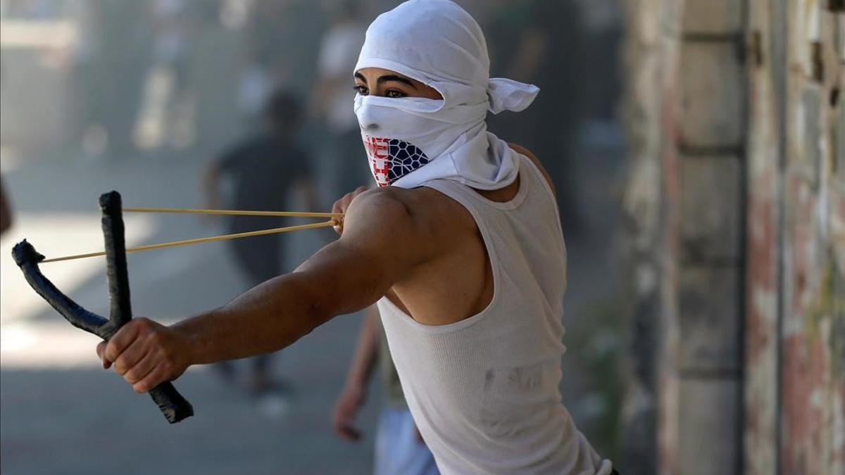 A Palestinian demonstrator uses a slingshot to hurl stones at Israeli forces during a protest over tension in Jerusalem and Israel-Gaza escalation  in Hebron in the Israeli-occupied West Bank  May 14  2021  REUTERS Mussa Qawasma