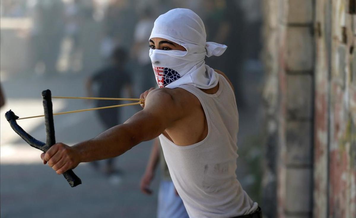 Un manifestante palesino lanza piedras a las fuerzas israelís durante las protestas en Hebrón