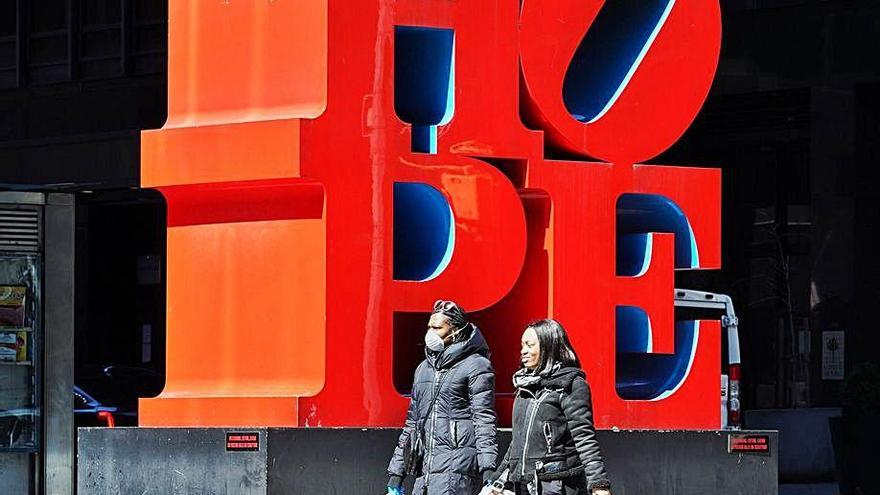 Dos mujeres pasan ante una escultura del artista Robert Indiana en Times Square con la palabra &#039;hope&#039; (esperanza).