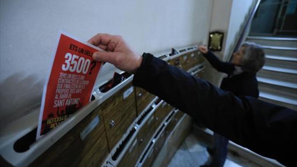 Elisa y Xavier depositan en los buzones de una finca de la calle de Rocafort folletos de la campaña contra el aumento exagerado de los alquileres de las viviendas del barrio.