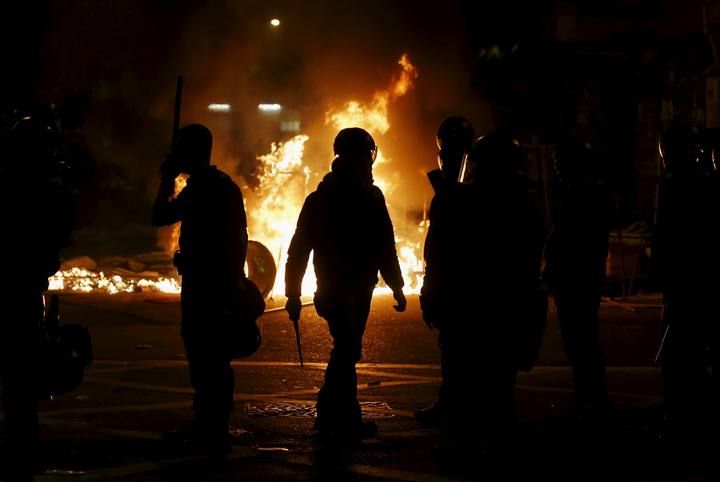 A riot policeman walks in front of a fire set by protesters at a junction in Mongkok district in Hong Kong