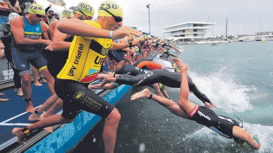 Varios participantes se lanzan al agua al inicio de un Triatlón en València.  | FRANCISCO CALABUIG