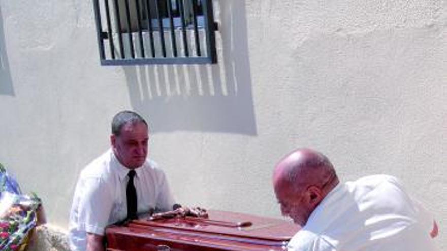 Los empleados de una funeraria desplazan un féretro.