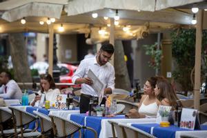 Un camarero atiende a dos clientas en una terraza en Barcelona.