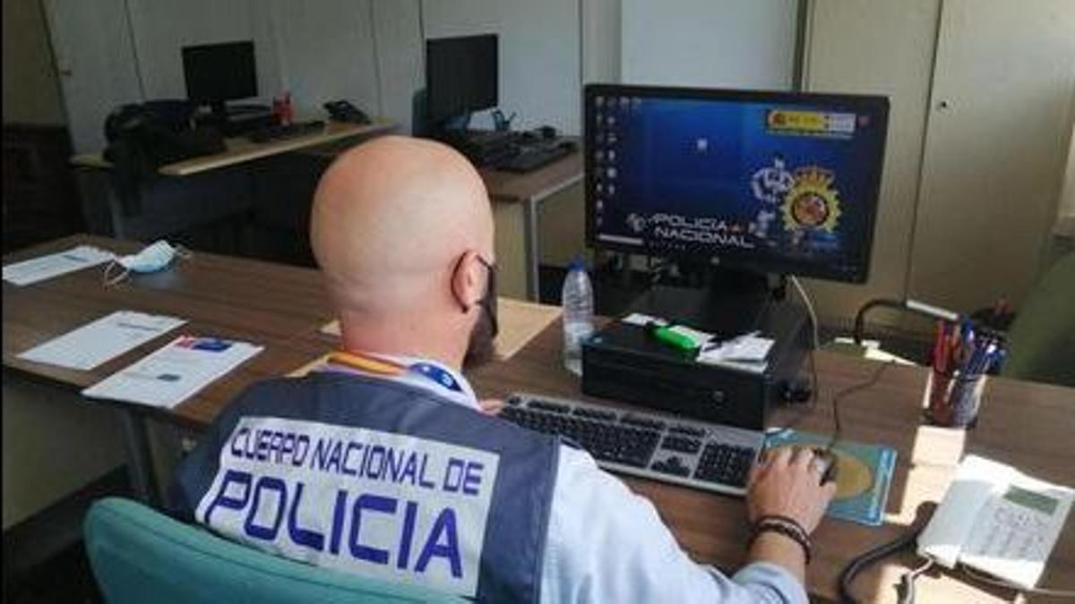 Un policía nacional investiga delante de un ordenador.