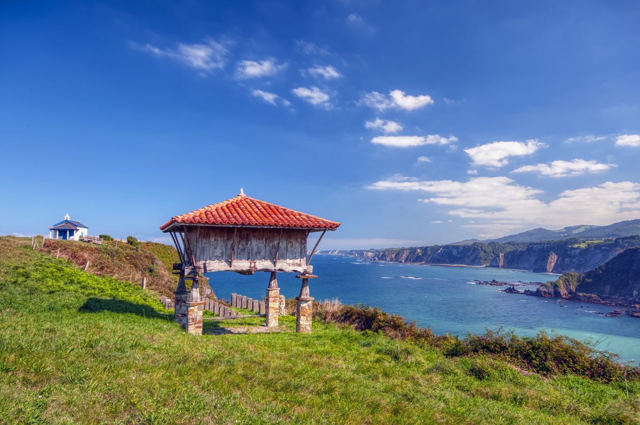La ermita de fondo, y en primer plano, un típico hórreo asturiano.