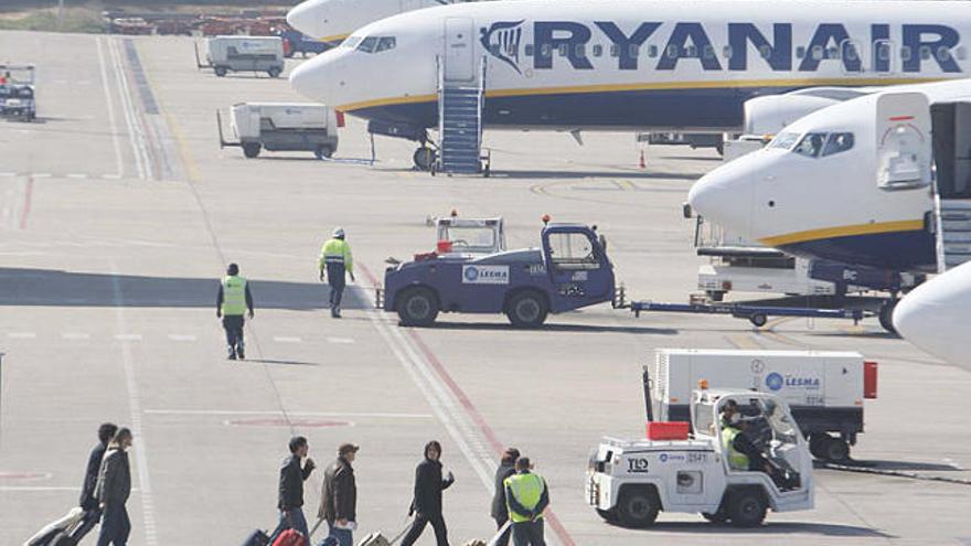 Passatgers dirigint-se als avions de Ryanair aparcats a la pista.