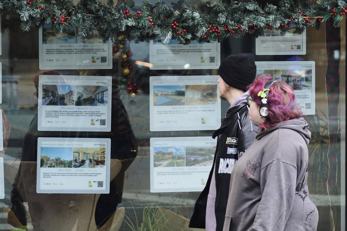 Dues persones davant l'aparador d'una immobiliària a Girona.