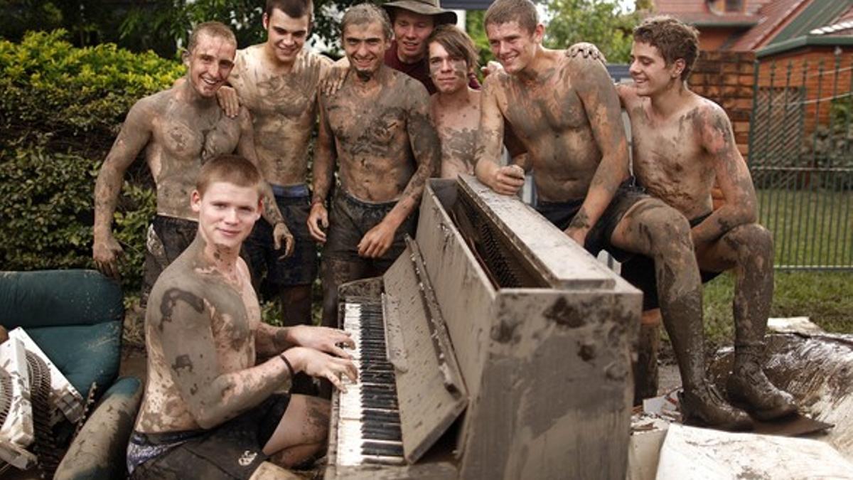 El joven Andrew Taylor (segundo por la derecha) y sus amigos hacen una pausa en sus trabajos de limpieza de la casa de sus padres, este viernes, en Brisbane.