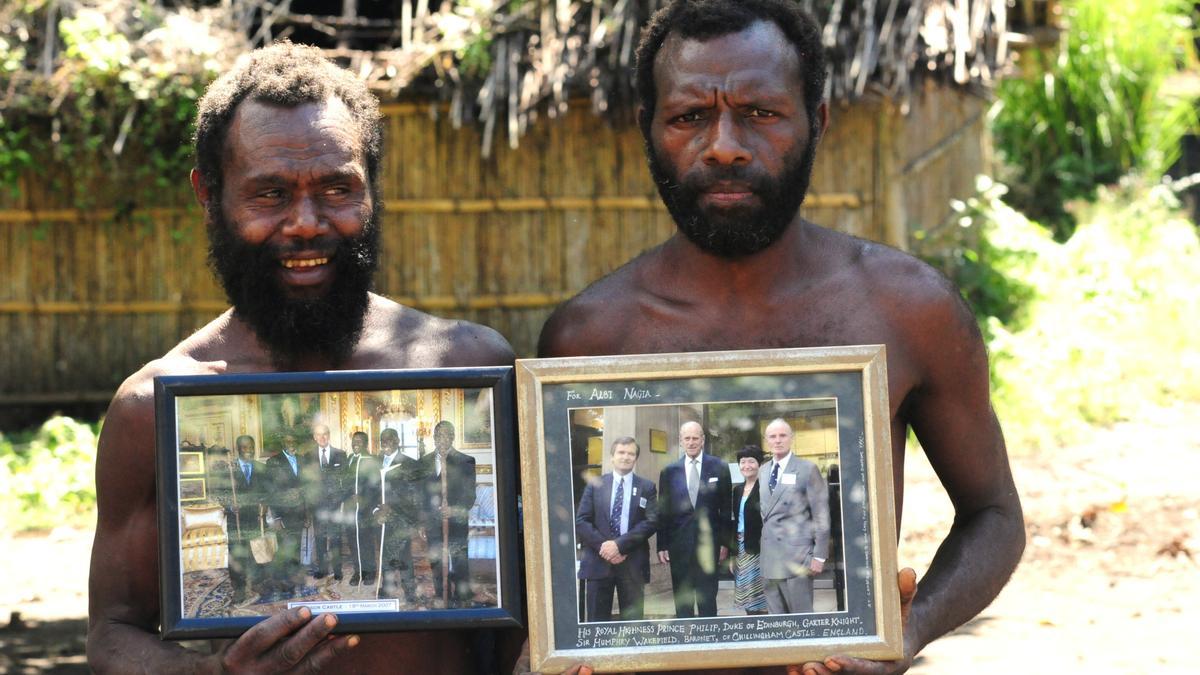 Dos miembros de una tribu en Yaohnanen muestran fotos enmarcadas de su visita en 2007 con el Príncipe Felipe de Edimburgo, su dios