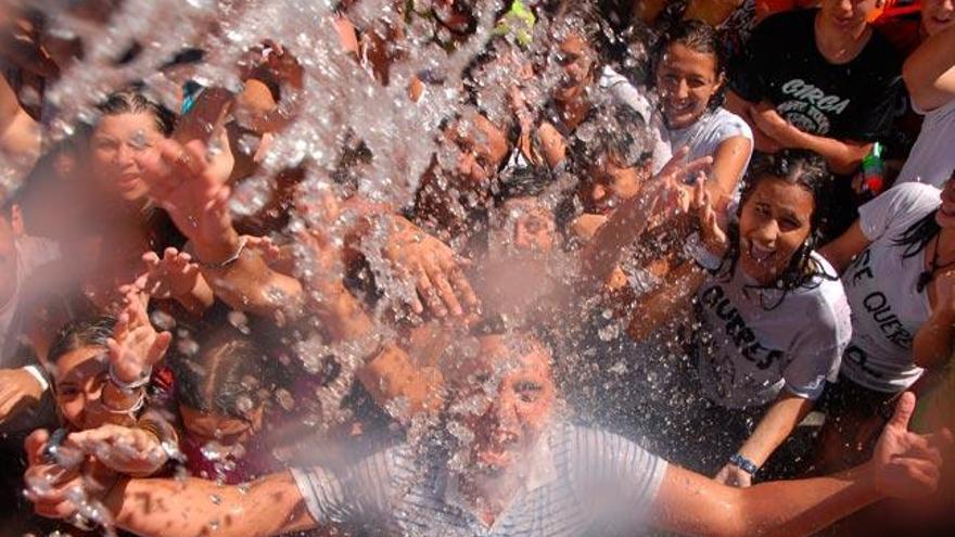 Asistentes a la fiesta bajo un chorro de agua. // Iñaki Abella