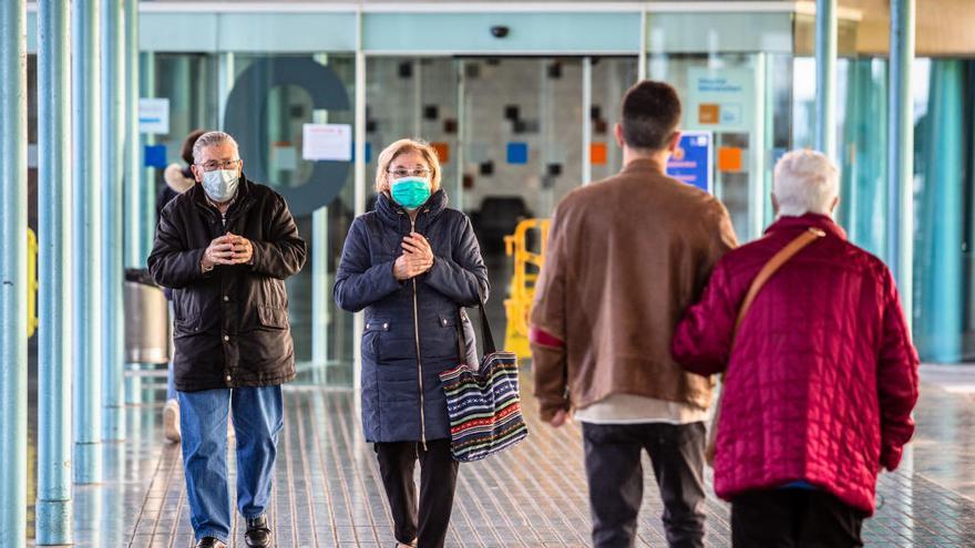 Los visitantes con máscaras de protección facial caminan por el Hospital del Mar en Barcelona.