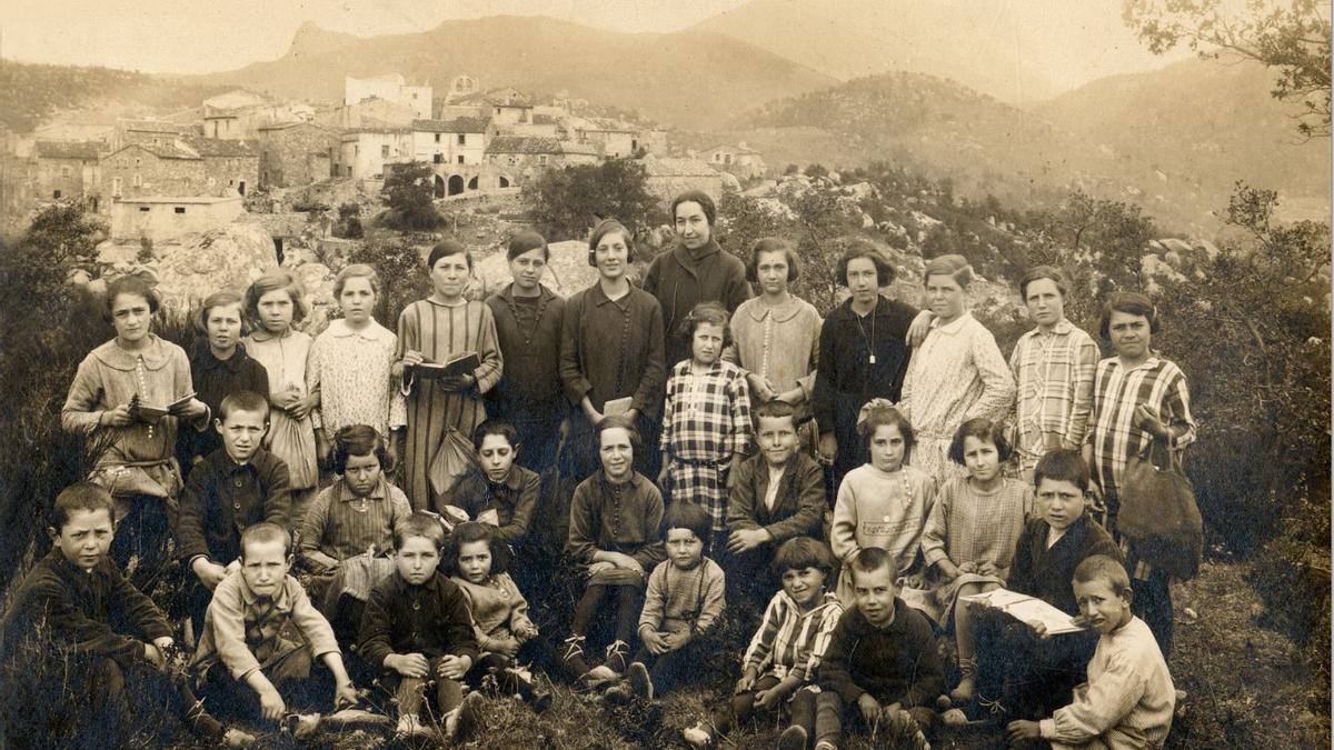 Extraordinària fotografia dels escolars i la professora de la Vajol, amb la silueta del seu poble darrere, l'any 1925, ara fa just cent anys.