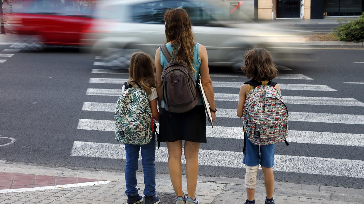 Una madre lleva a sus hijos al colegio.