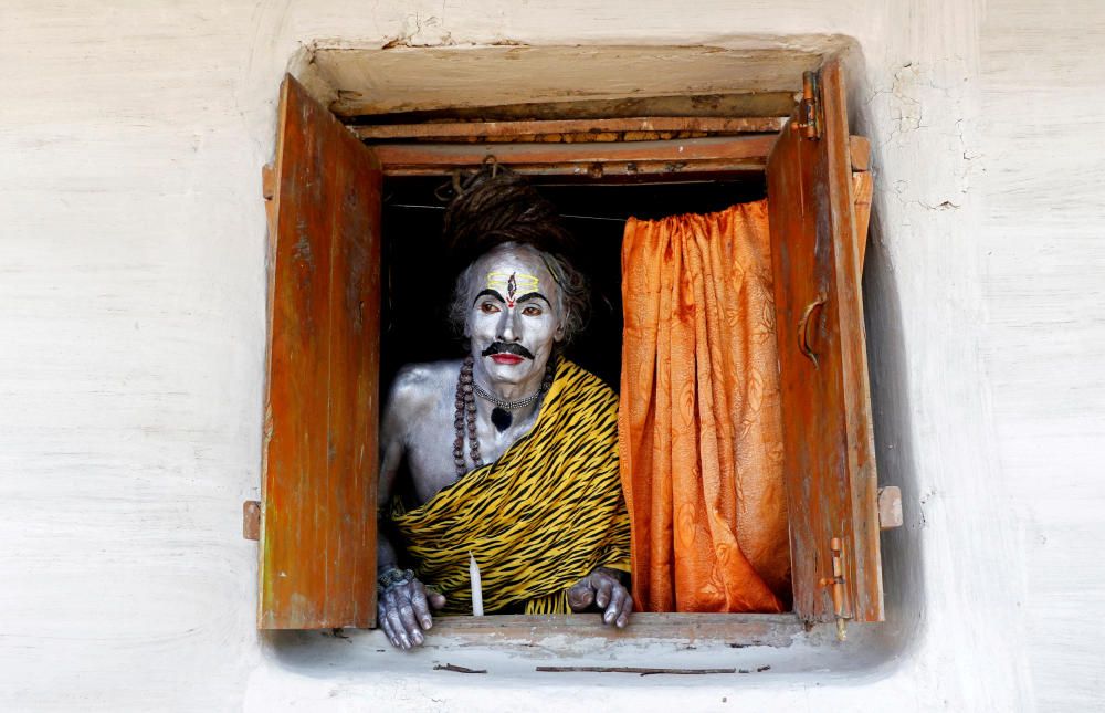 A devotee, dressed as Hindu God Shiva, looks out ...