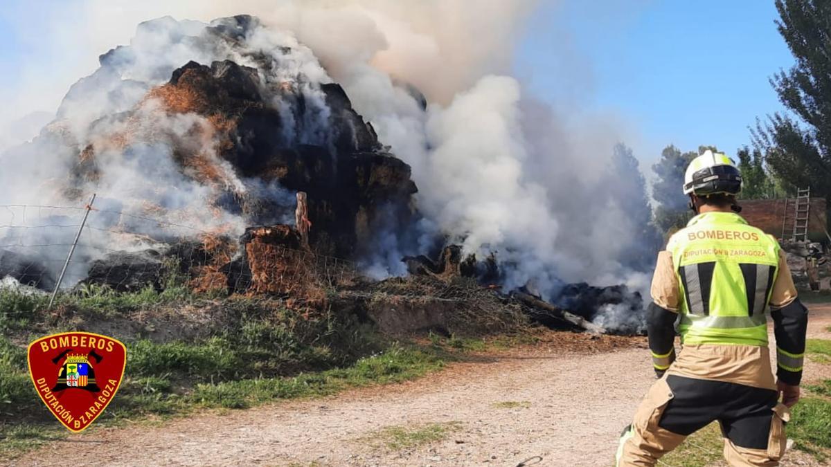 Un bombero dirige el agua hacia el montón de paja en llamas.