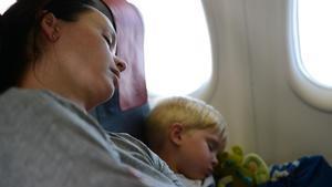 Una mujer duerme con su hijo en un avión.