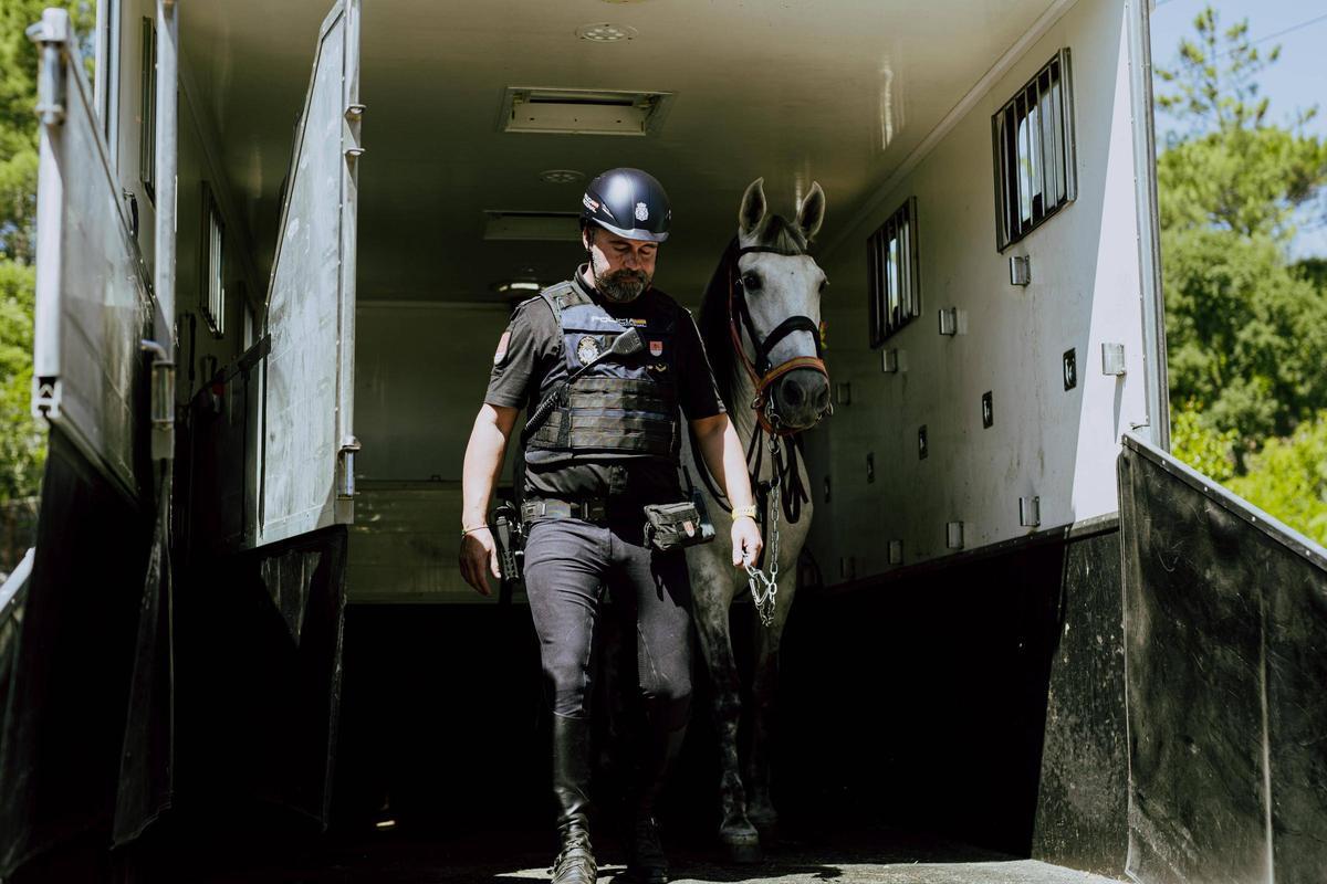El agente ourensano Emilio Rodríguez desciende del camión policial con uno de los equinos de la unidad.