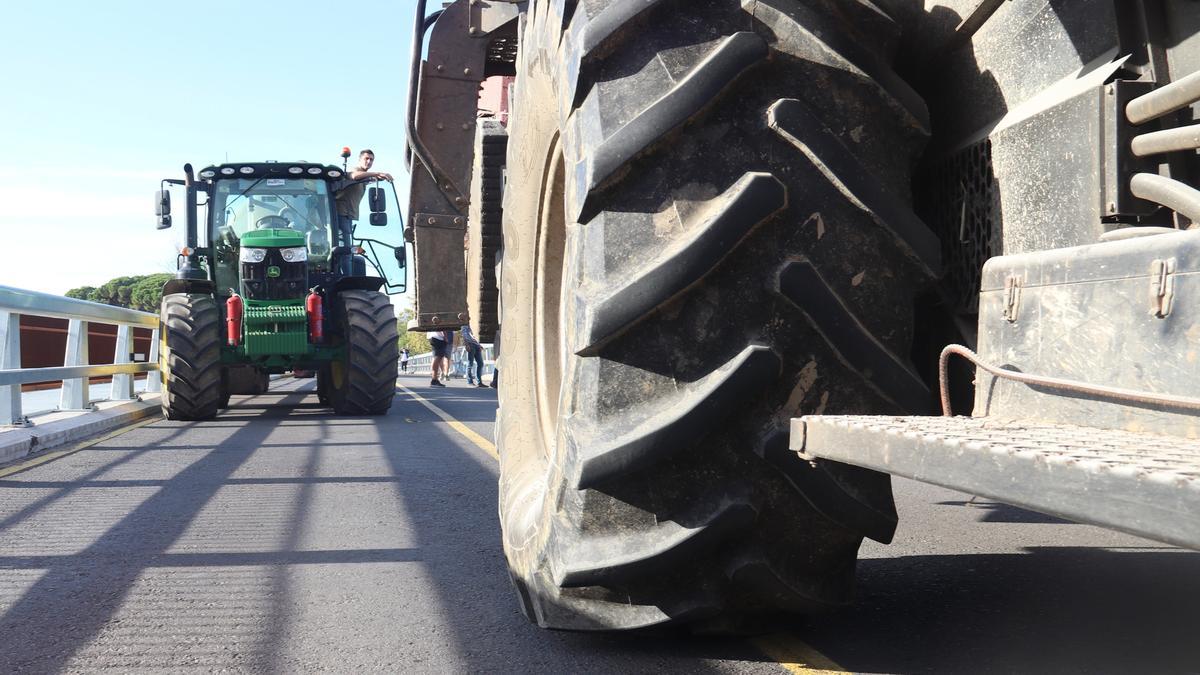 Un tractor amb remolc ocupa part del carril contrari en el pont sobre el Ter a Verges mentre un tractor que ve de cares intenta passar sense tenir espai