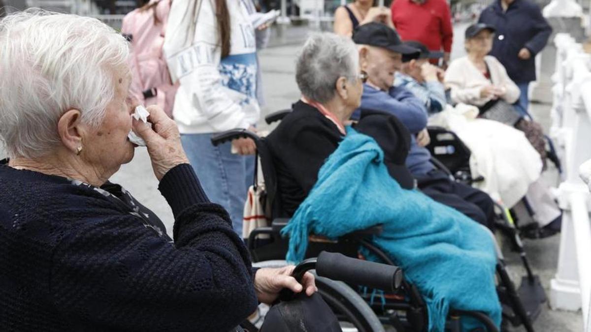 Varios de los mayores observan el mar en Gijón.