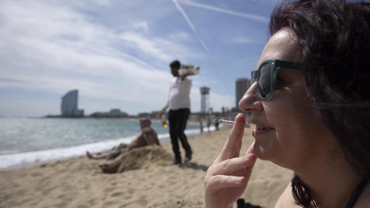 Una mujer fumando en una playa de Barcelona