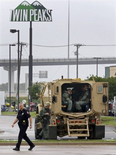 A police officer walks past a SWAT truck in the parking lot of a Twin Peaks restaurant where nine members of a motorcycle gang were shot and killed in Waco