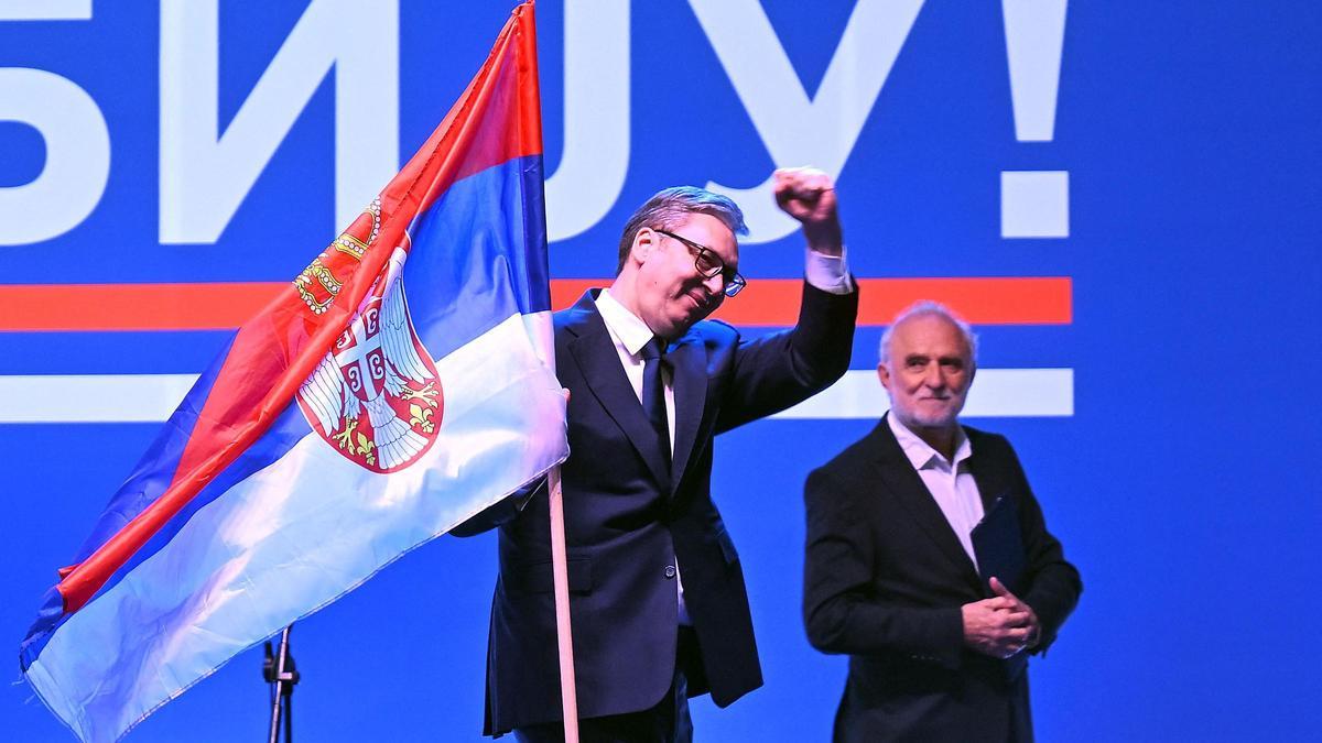 El presidente de Serbia, Aleksandar Vucic (izq.), sostiene una bandera serbia en un mitin en Belgrado.