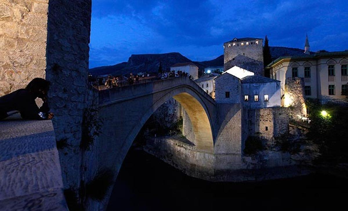 Unos turistas pasean este jueves por el puente situado en el casco viejo de Mostar (Bosnia-Herzegovina). Destruido durante la guerra de Bosnia, este puente simboliza la unión entre las dos culturas existentes en la ciudad, católicos croatas al oeste  y musulmanes bosnios al este.