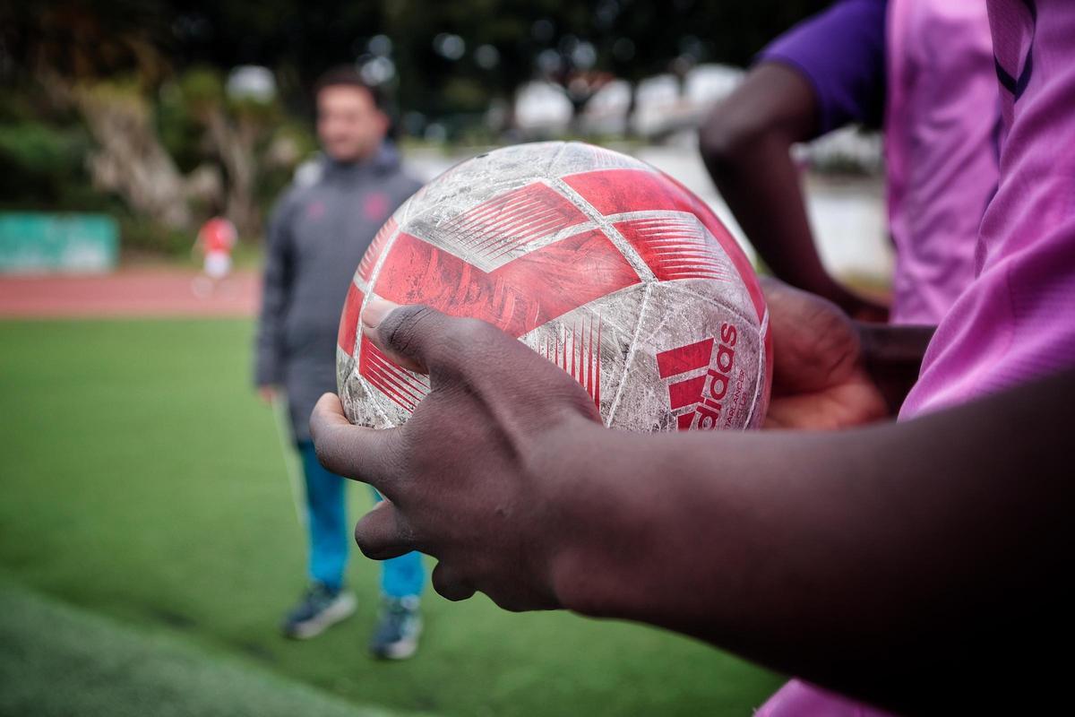 Un joven migrante sostiene un balón de fútbol.