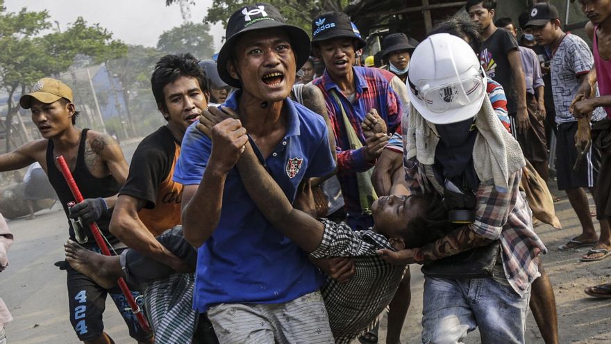 Hombres recogen a un compañero herido en protestas en Birmania.